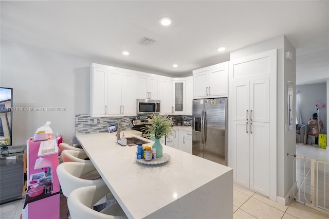 3289 W 106th Ter, Hialeah, FL 33018 - kitchen with a sink, visible vents, a peninsula, light countertops, and appliances with stainless steel finishes