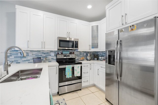 3289 W 106th Ter, Hialeah, FL 33018 - kitchen with decorative backsplash, light tile patterned floors, appliances with stainless steel finishes, a sink, and white cabinetry