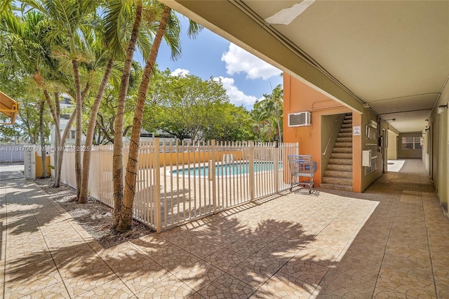view of pool featuring fence, a fenced in pool, a wall mounted air conditioner, and a patio area