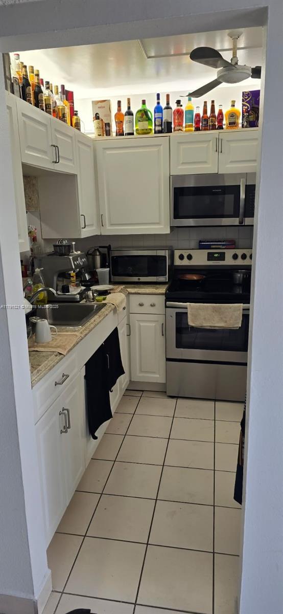 4805 NW 35th St Unit 610, Lauderdale Lakes, FL 33319 - kitchen featuring appliances with stainless steel finishes, light tile patterned floors, white cabinetry, light countertops, and ceiling fan