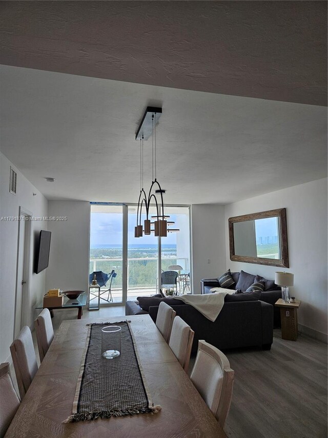 dining room with visible vents, baseboards, wood finished floors, and a wall of windows