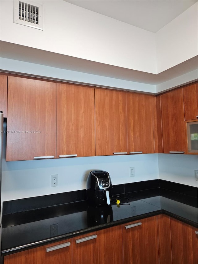 kitchen with visible vents, modern cabinets, brown cabinets, and dark countertops