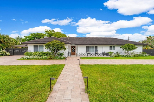 single story home featuring stucco siding, a carport, a porch, and a front lawn