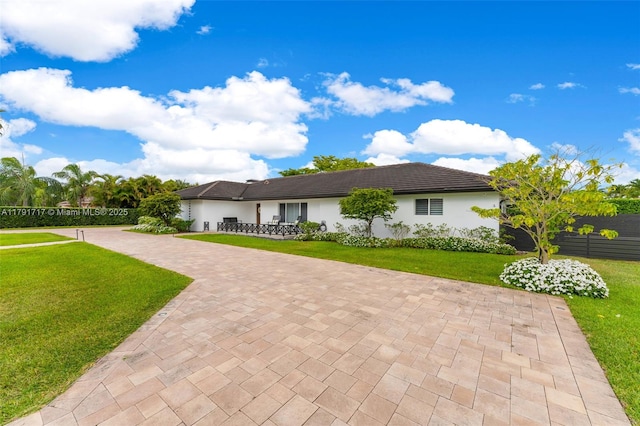 ranch-style home with fence, stucco siding, and a front yard
