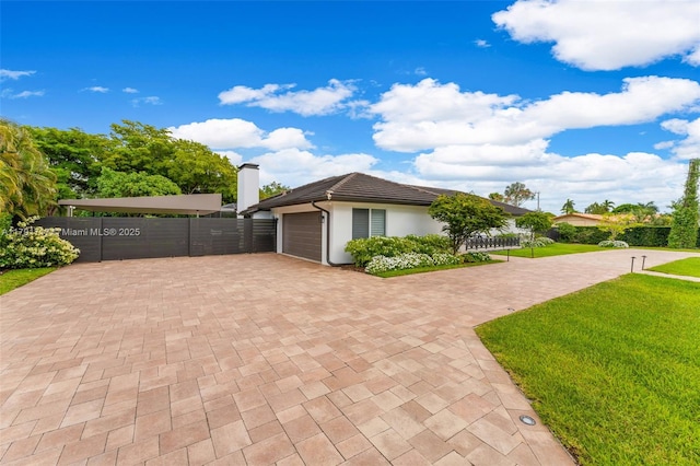 exterior space with stucco siding, decorative driveway, fence, a yard, and a garage