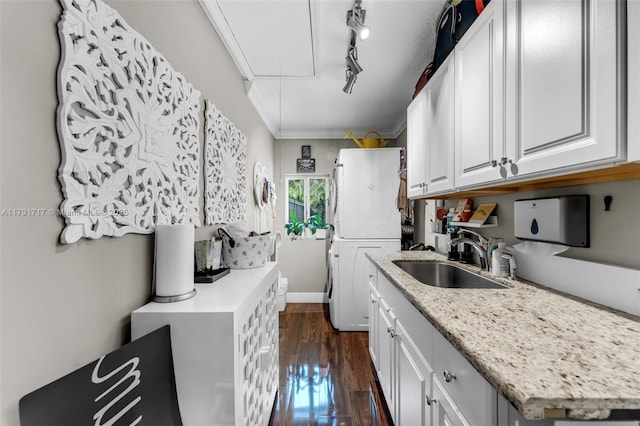 kitchen with a sink, rail lighting, dark wood-type flooring, crown molding, and white cabinetry