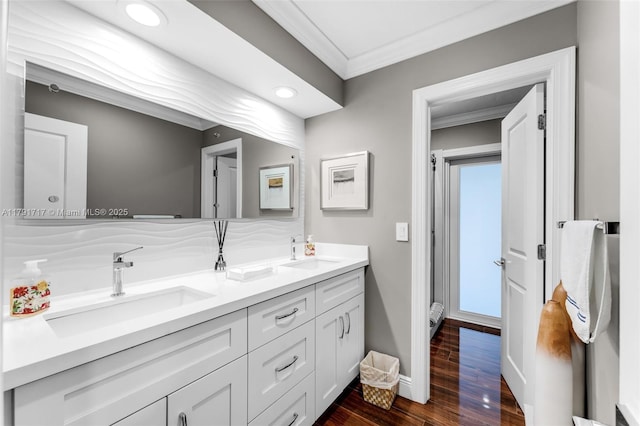 full bathroom with double vanity, wood finished floors, crown molding, and a sink