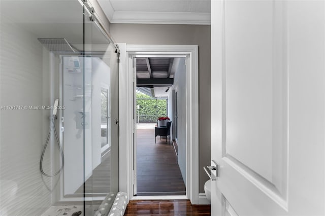bathroom featuring baseboards, wood finished floors, walk in shower, and crown molding
