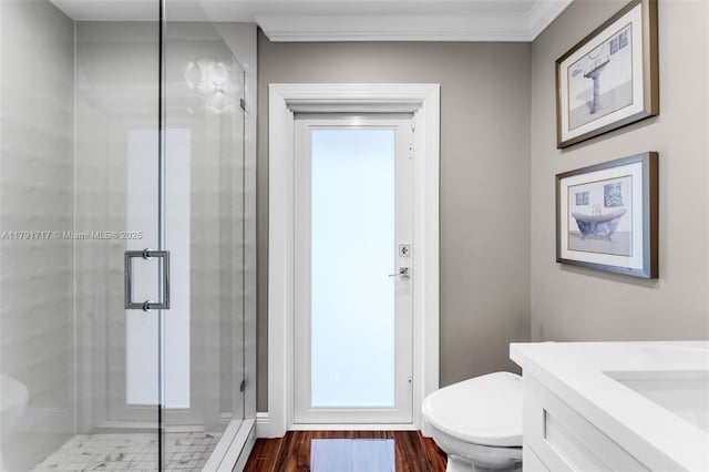bathroom featuring wood finished floors, a shower stall, ornamental molding, toilet, and vanity