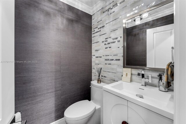 half bath with tasteful backsplash, crown molding, toilet, tile walls, and vanity