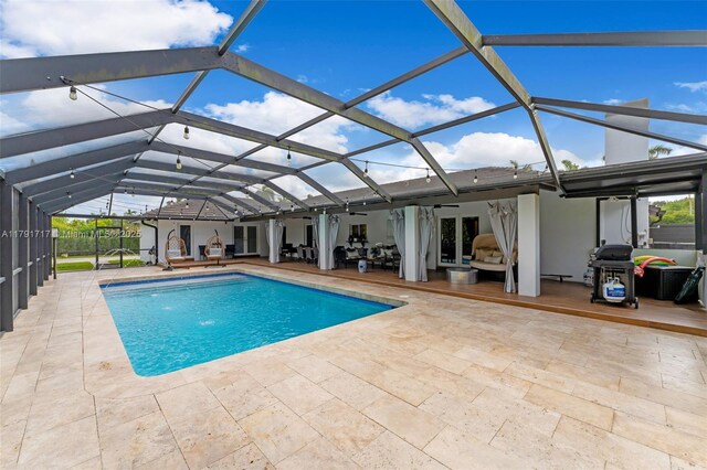 pool with outdoor lounge area, a patio area, french doors, and glass enclosure