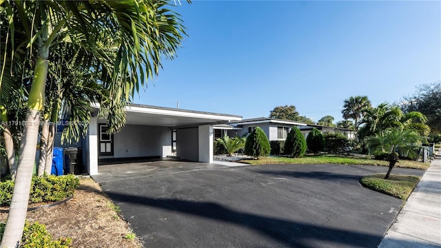 view of front of home with aphalt driveway, stucco siding, and a carport