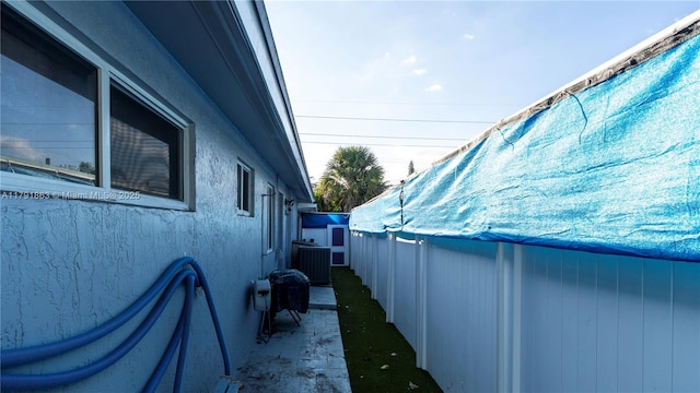 view of home's exterior featuring stucco siding, central AC unit, and a swimming pool