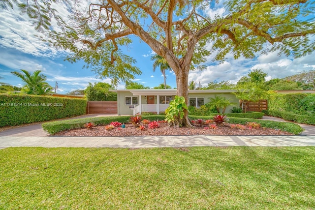 ranch-style home with a front lawn and fence
