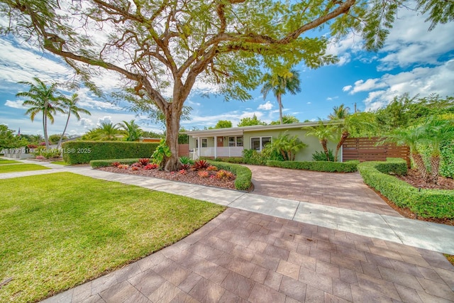 ranch-style home with stucco siding, decorative driveway, a front lawn, and fence