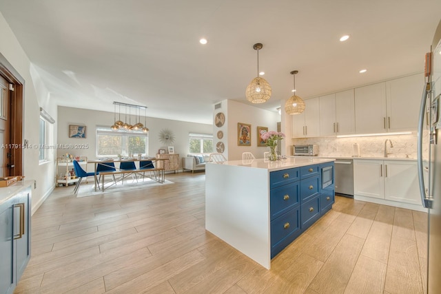 kitchen featuring light wood finished floors, dishwasher, light countertops, blue cabinetry, and white cabinetry