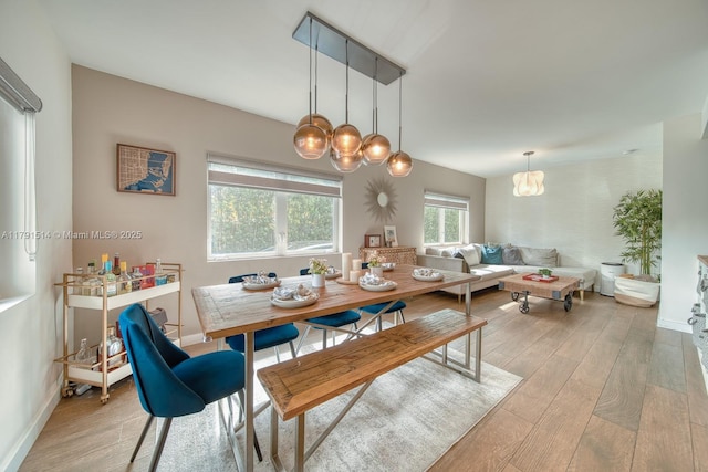 dining area with baseboards, a notable chandelier, and light wood finished floors