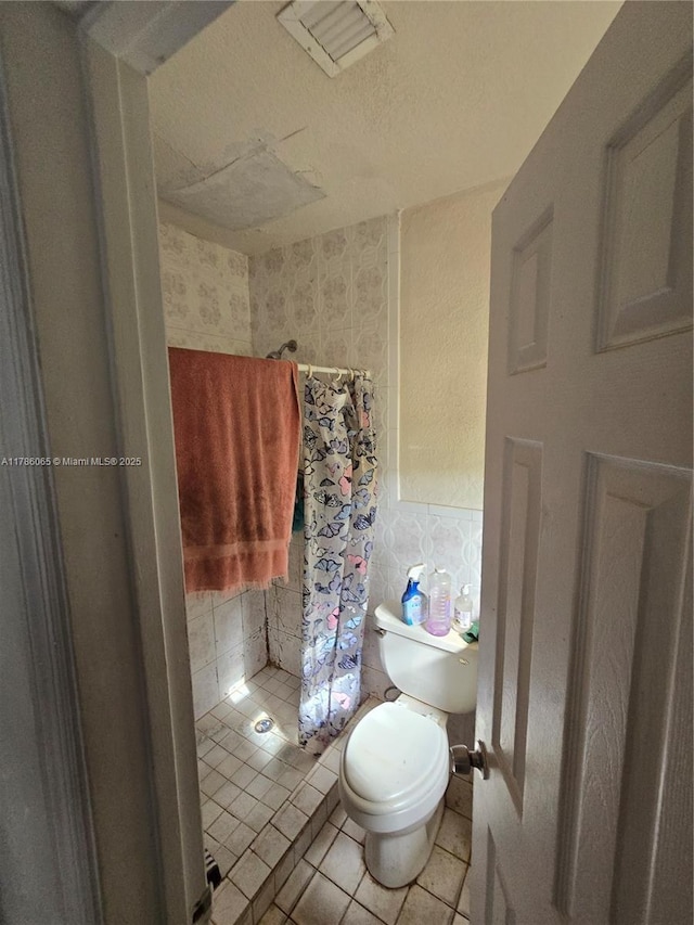 bathroom with tile patterned floors, toilet, and a shower with curtain