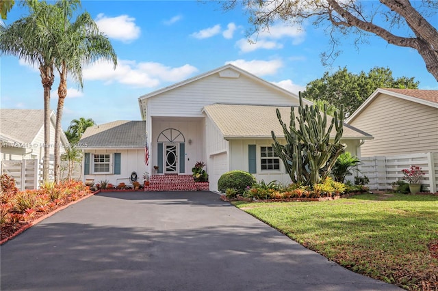 ranch-style home with a garage, roof with shingles, driveway, and a front yard