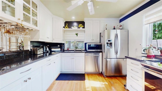 kitchen featuring ceiling fan, appliances with stainless steel finishes, a sink, white cabinets, and light wood-style flooring