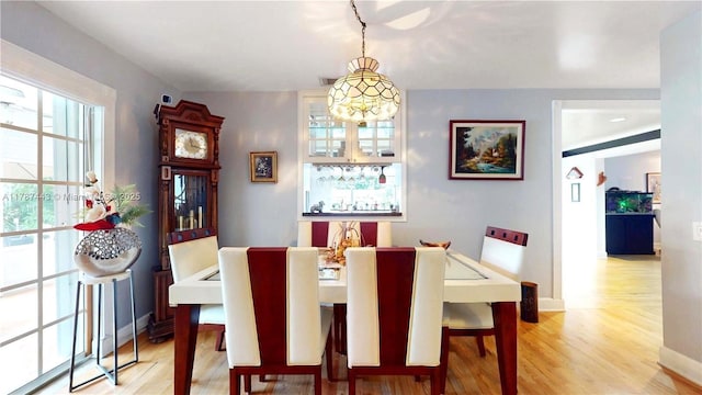 dining space with light wood-type flooring, baseboards, and a chandelier