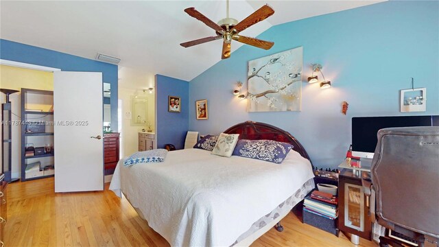 bedroom featuring visible vents, ensuite bathroom, lofted ceiling, and wood finished floors