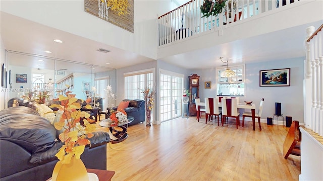 living room with plenty of natural light, stairs, wood finished floors, and visible vents