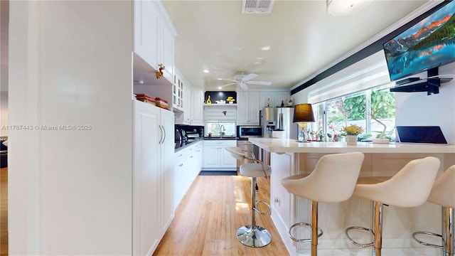 kitchen featuring visible vents, open shelves, a peninsula, white cabinets, and appliances with stainless steel finishes