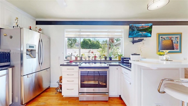 kitchen with crown molding, appliances with stainless steel finishes, dark countertops, light wood-type flooring, and white cabinets