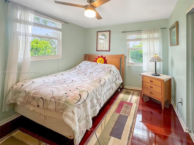 bedroom with ceiling fan, baseboards, multiple windows, and wood finished floors