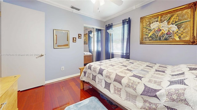 bedroom featuring ceiling fan, visible vents, crown molding, wood finished floors, and a closet