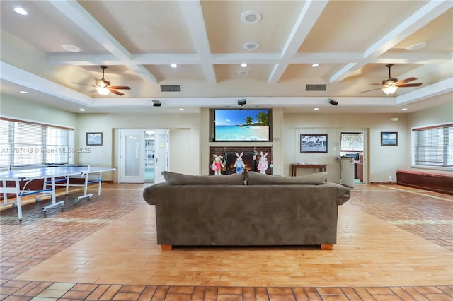 living area featuring coffered ceiling, a ceiling fan, and visible vents