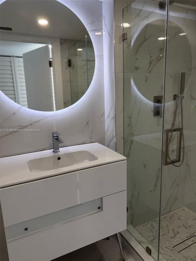 bathroom with recessed lighting, a marble finish shower, and vanity