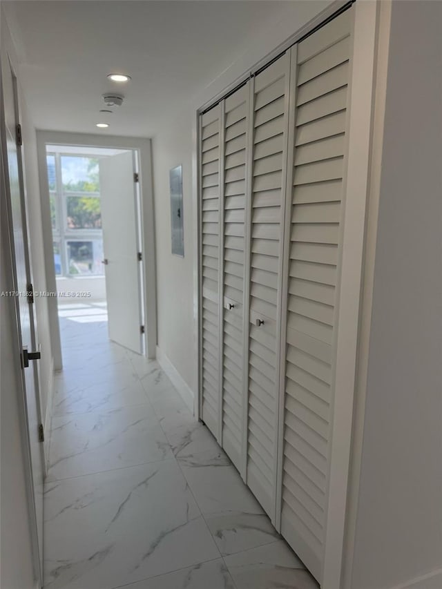 corridor featuring recessed lighting, electric panel, marble finish floor, and baseboards
