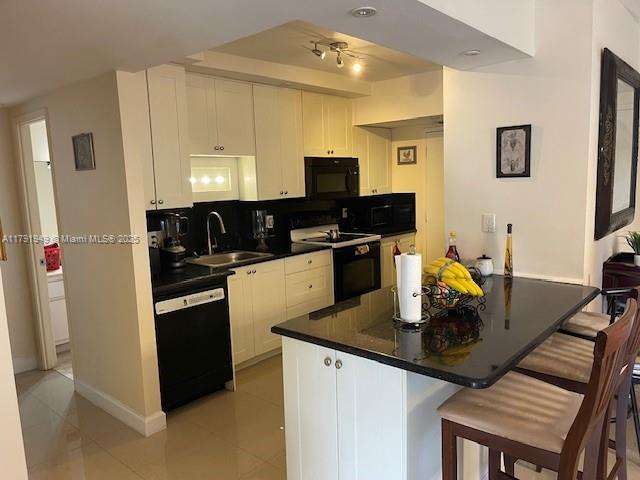 4400 Hillcrest Dr Unit 701B, Hollywood, FL 33021 - kitchen featuring dark countertops, a kitchen bar, white cabinets, a sink, and black appliances