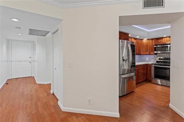 300 SW 130th Ter Unit 203B, Pembroke Pines, FL 33027 - kitchen with appliances with stainless steel finishes, crown molding, backsplash, brown cabinets, and light wood finished floors