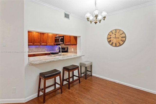 300 SW 130th Ter Unit 203B, Pembroke Pines, FL 33027 - kitchen featuring appliances with stainless steel finishes, a chandelier, backsplash, brown cabinetry, and a breakfast bar area