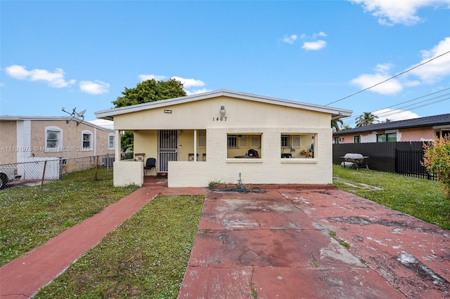 bungalow-style home featuring stucco siding, brick siding, a front yard, and fence private yard