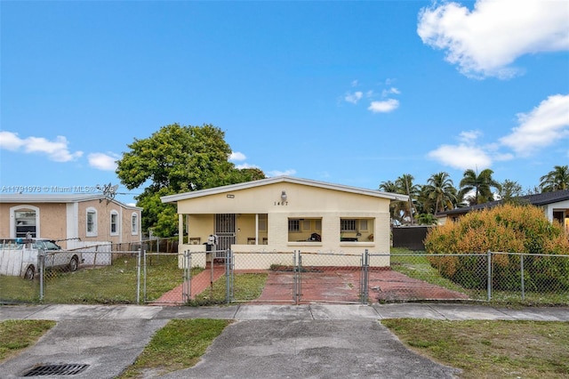 bungalow-style home featuring a front yard, stucco siding, a fenced front yard, and a gate