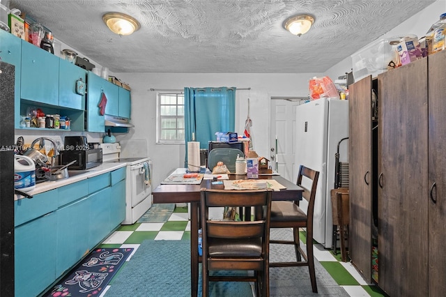 kitchen with light countertops, under cabinet range hood, blue cabinetry, light floors, and white appliances