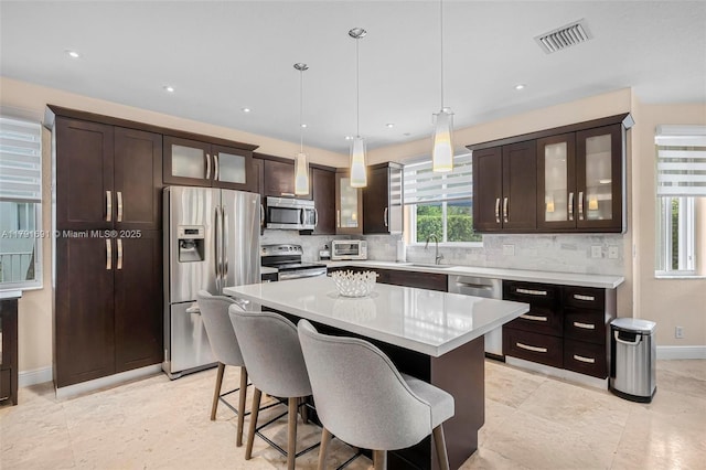 943 Golden Cane Dr, Weston, FL 33327 - kitchen with tasteful backsplash, a breakfast bar area, appliances with stainless steel finishes, dark brown cabinets, and visible vents
