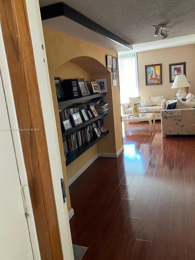 hallway featuring a textured ceiling and dark wood finished floors