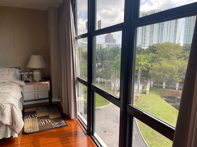 bedroom featuring a view of city, multiple windows, and wood finished floors