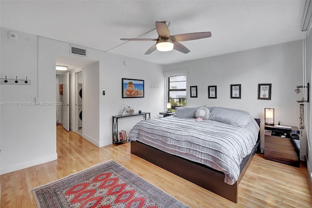 100 Ocean Lane Dr Unit 301, Key Biscayne, FL 33149 - bedroom featuring stacked washing maching and dryer, light wood-type flooring, baseboards, visible vents, and a ceiling fan