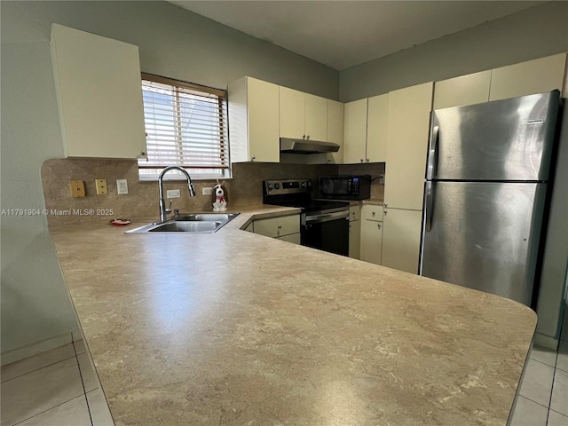 kitchen featuring under cabinet range hood, appliances with stainless steel finishes, decorative backsplash, and a sink