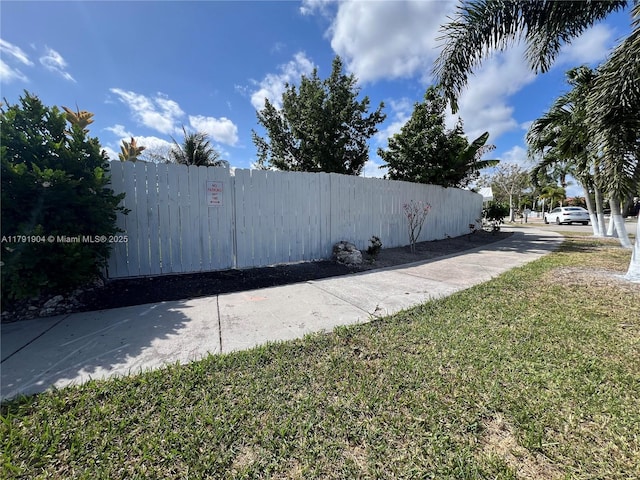 view of side of home with fence and a yard