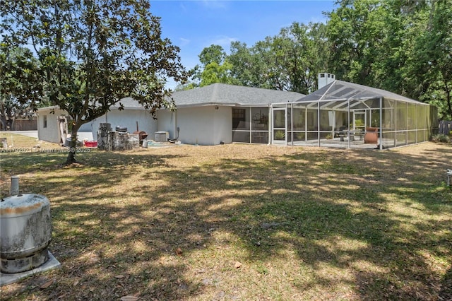 rear view of house with a lawn, central air condition unit, and glass enclosure