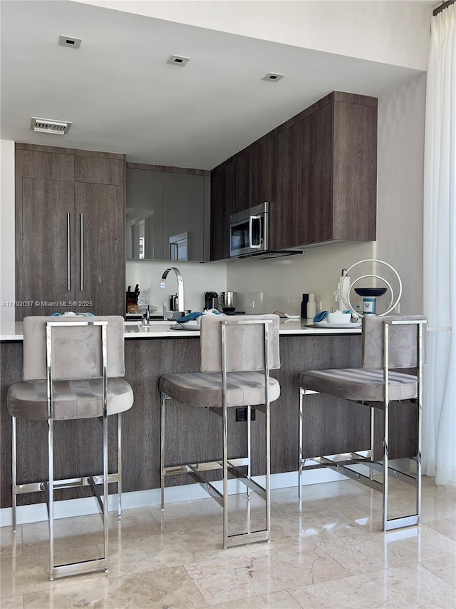 68 SE 6th St Unit 3611, Miami, FL 33131 - kitchen with light countertops, stainless steel microwave, modern cabinets, and a kitchen breakfast bar
