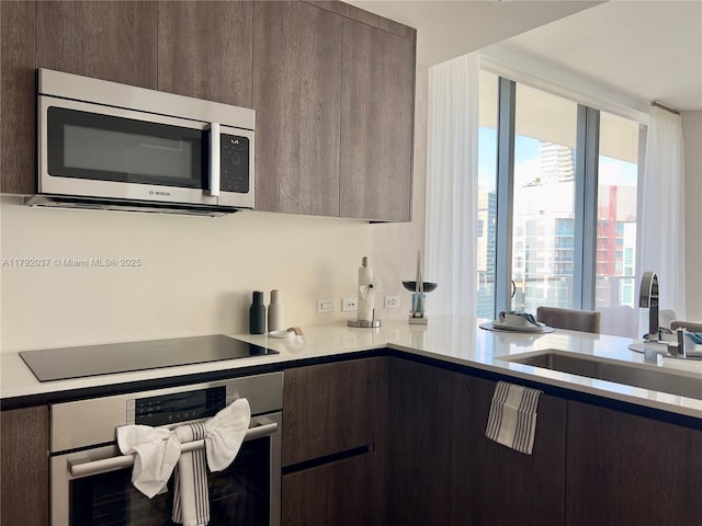 68 SE 6th St Unit 3611, Miami, FL 33131 - kitchen featuring dark brown cabinetry, appliances with stainless steel finishes, a sink, light countertops, and modern cabinets