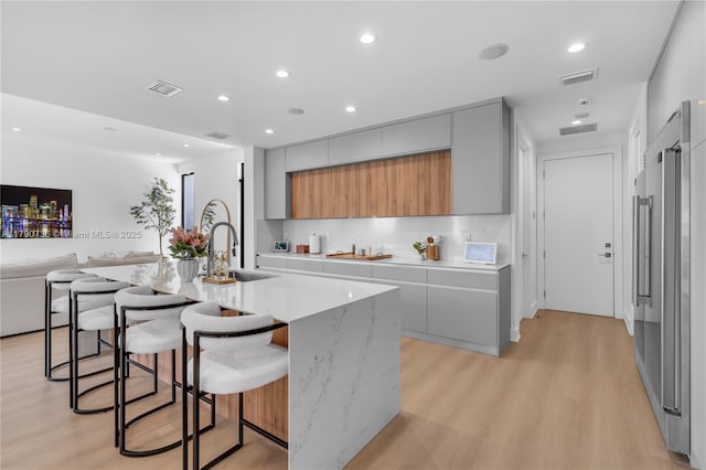 1509 SW 15th St, Miami, FL 33145 - kitchen featuring light wood finished floors, modern cabinets, a sink, gray cabinets, and visible vents